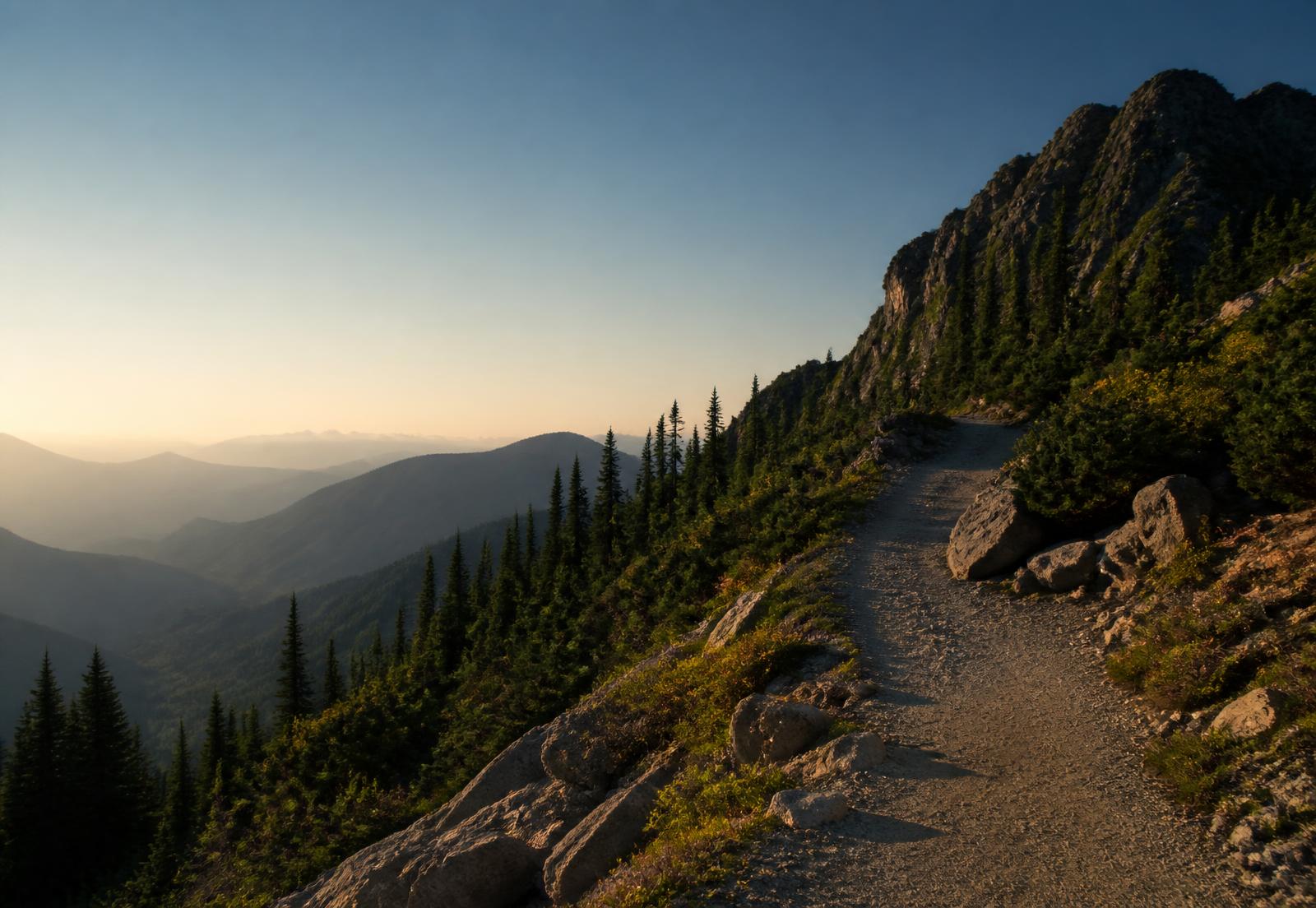 A mountain trail opening toward a distant horizon